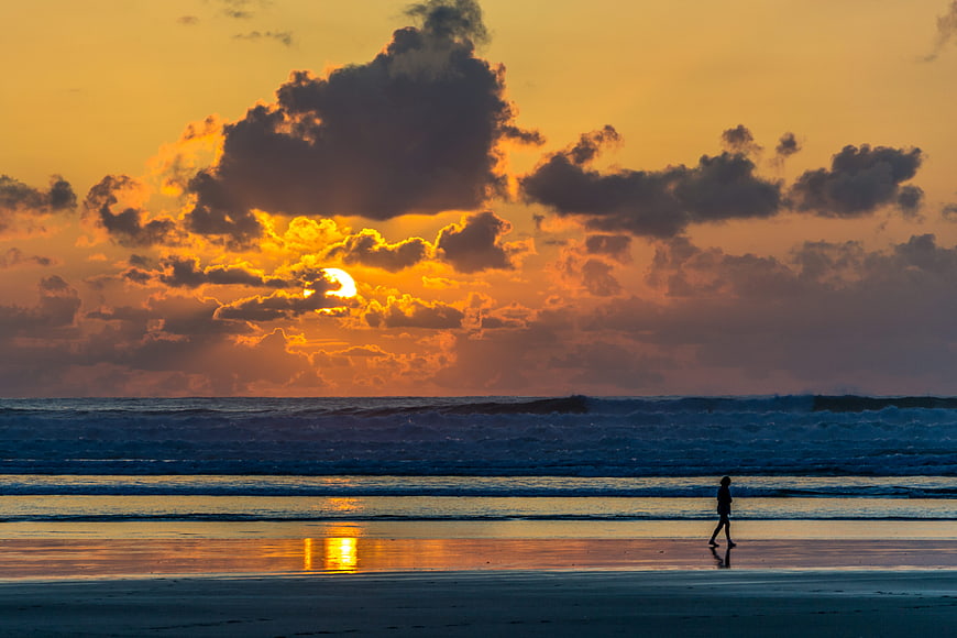 Silhouette of Woman Walking on Beach at Sunset