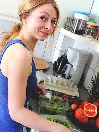 Smiling woman preparing healthy salad and fruit in a home kitchen