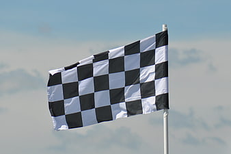 Checkered racing flag waving against blue sky
