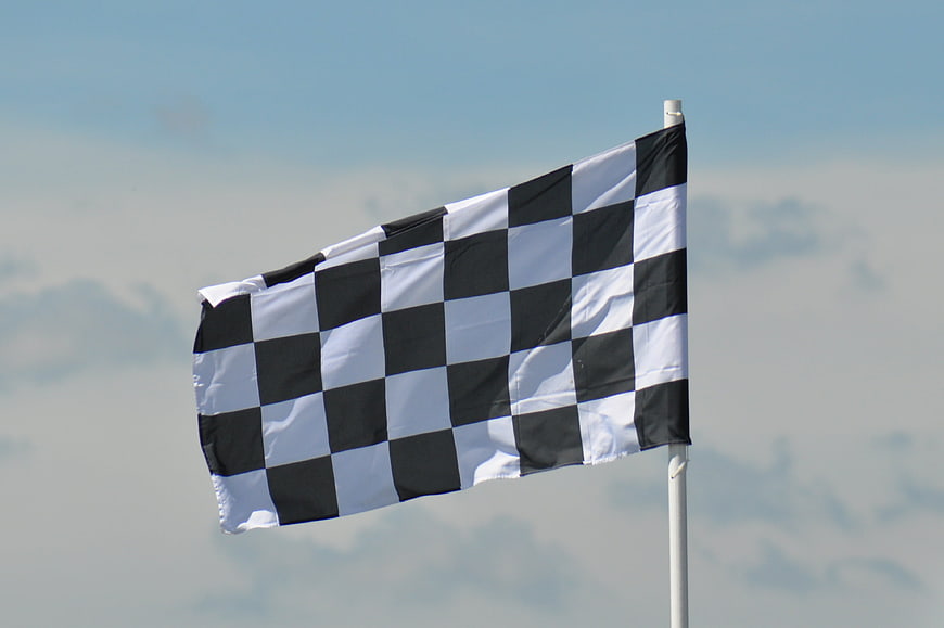 Checkered racing flag waving against blue sky