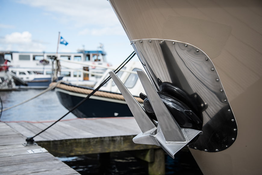 Close-up of stainless steel boat anchor at wooden dock