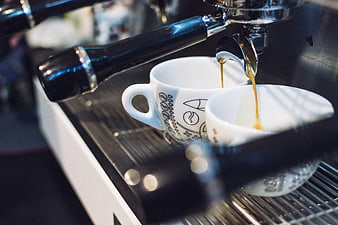 Espresso pouring into white cups from portafilter