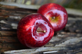 Two shiny red apples on rustic wooden surface