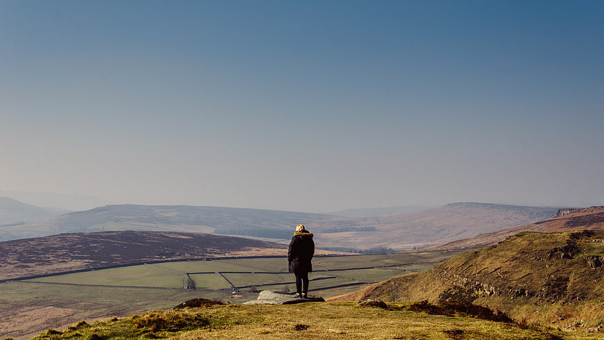 Lone Hiker Overlooking Vast Highland Valley Landscape