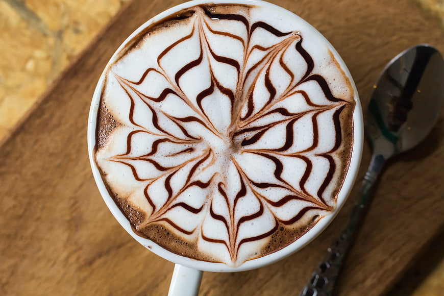 Top View Cappuccino with Intricate Latte Art on Wooden Table