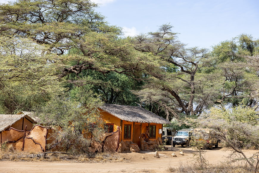 Rustic African Safari Lodge with Thatched Roof and Safari Vehicles