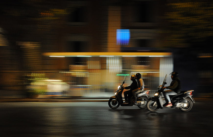 Motion blur of scooters riding on a city street at night