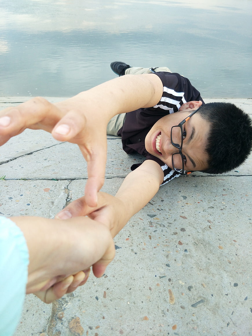 Boy lying on concrete reaching hand for help