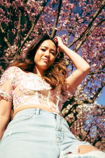 Young Woman in Floral Top Under Pink Blossom Tree