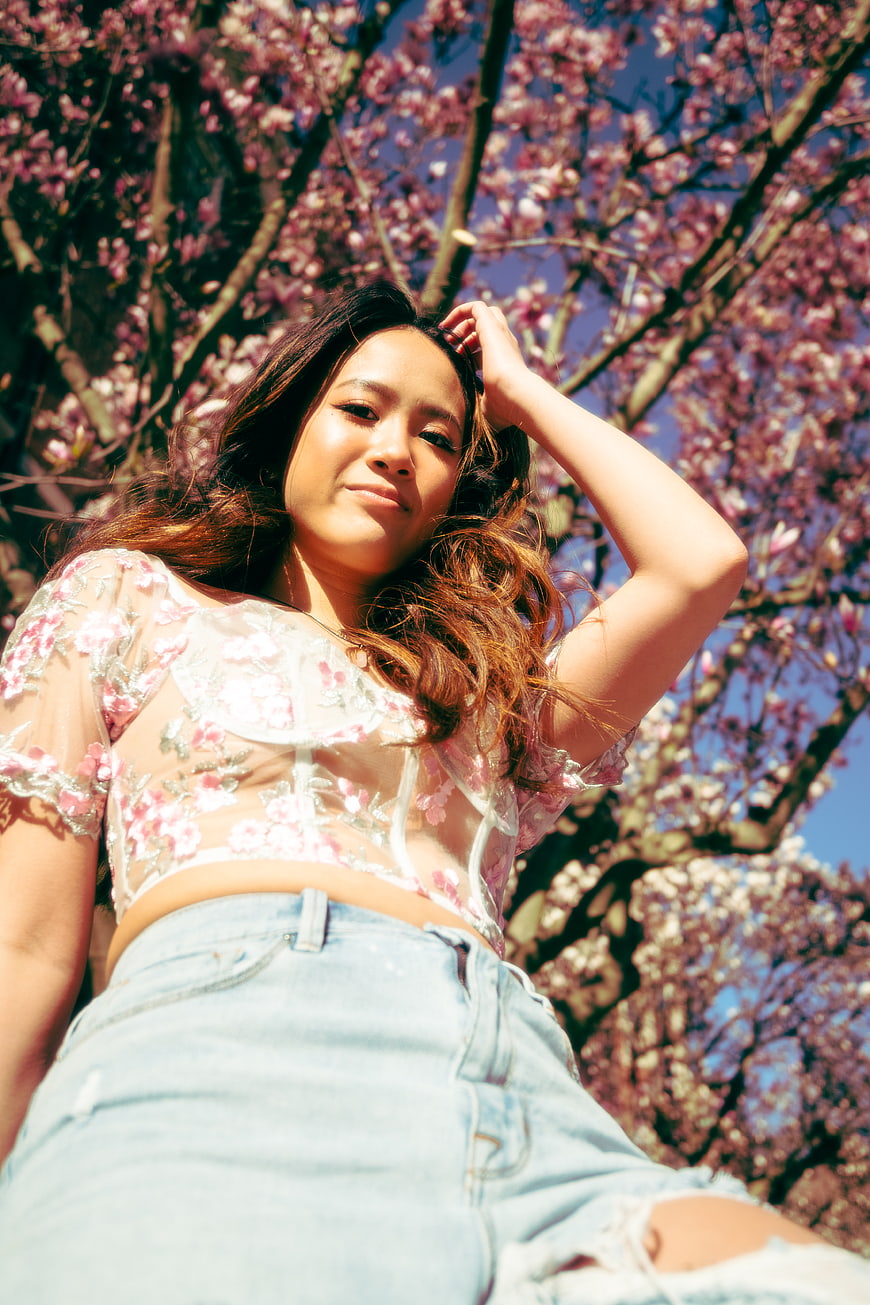 Young Woman in Floral Top Under Pink Blossom Tree