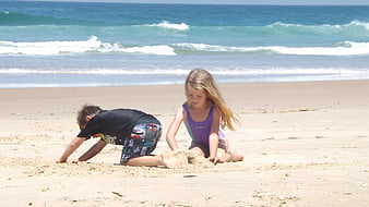 Two children playing in the sand on a sunny beach