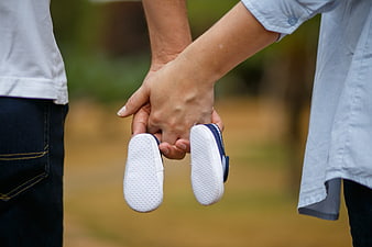 Couple holding baby shoes outdoors