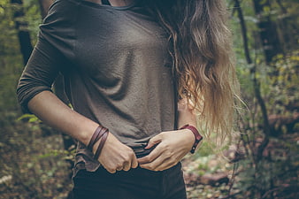 Woman in forest with long hair and leather bracelets