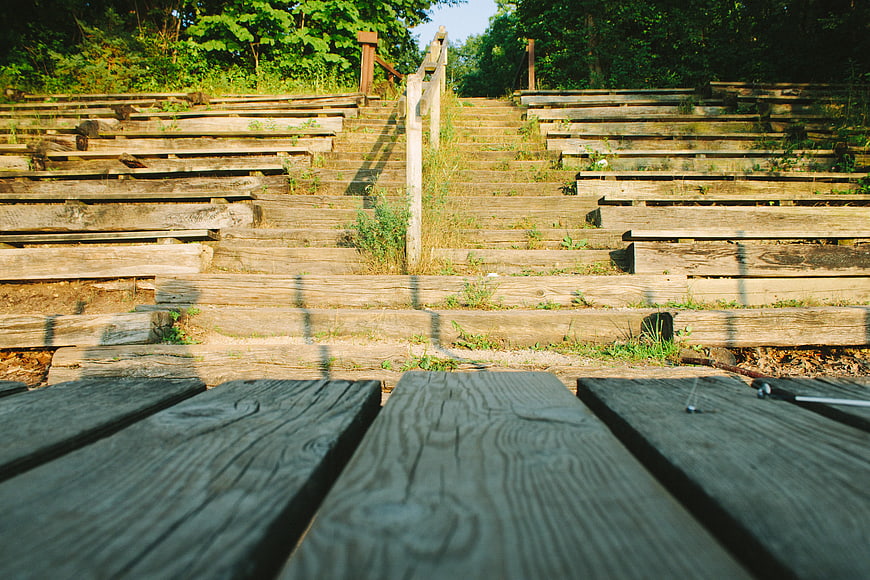 Weathered wooden amphitheater steps in a sunlit forest