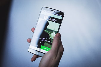 Hand holding smartphone displaying Spotify app login screen