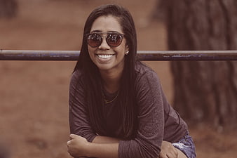 Smiling woman wearing sunglasses leaning on railing outdoors