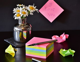 Pink sticky note with I love you message and daisies