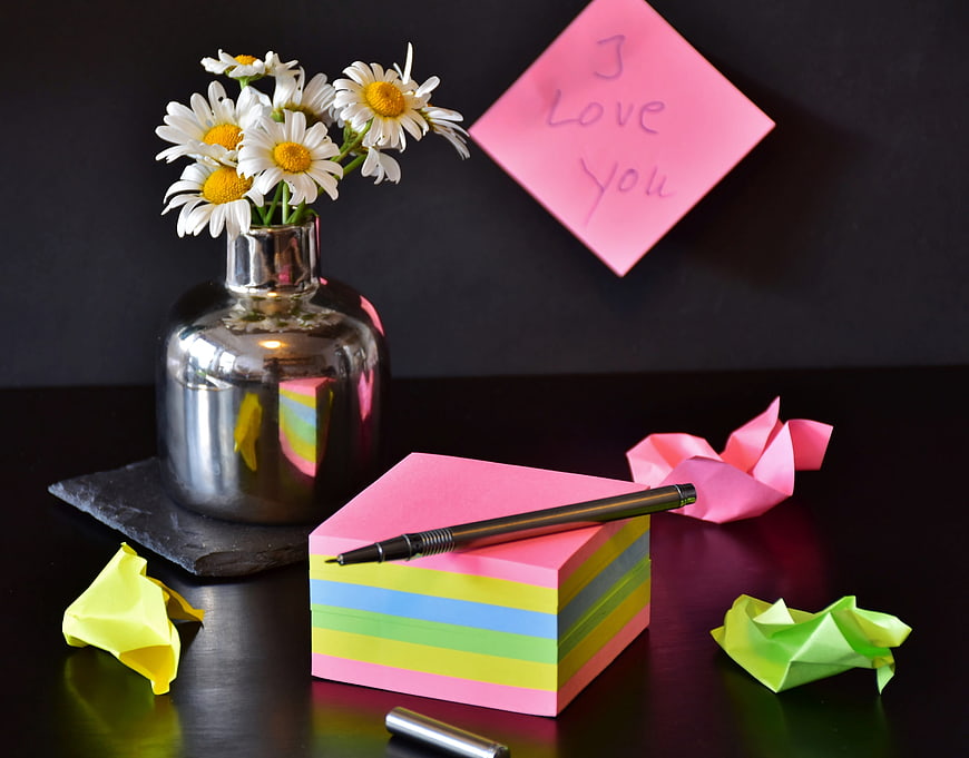 Pink sticky note with I love you message and daisies