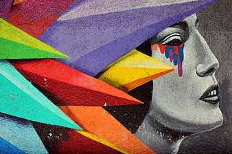 Colorful street art mural of crying woman with geometric shapes