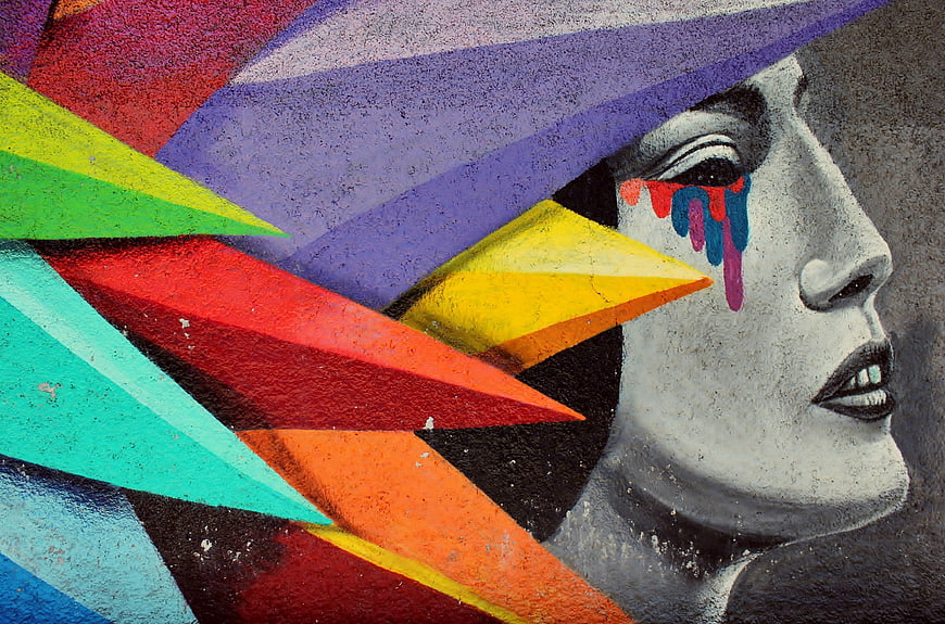 Colorful street art mural of crying woman with geometric shapes