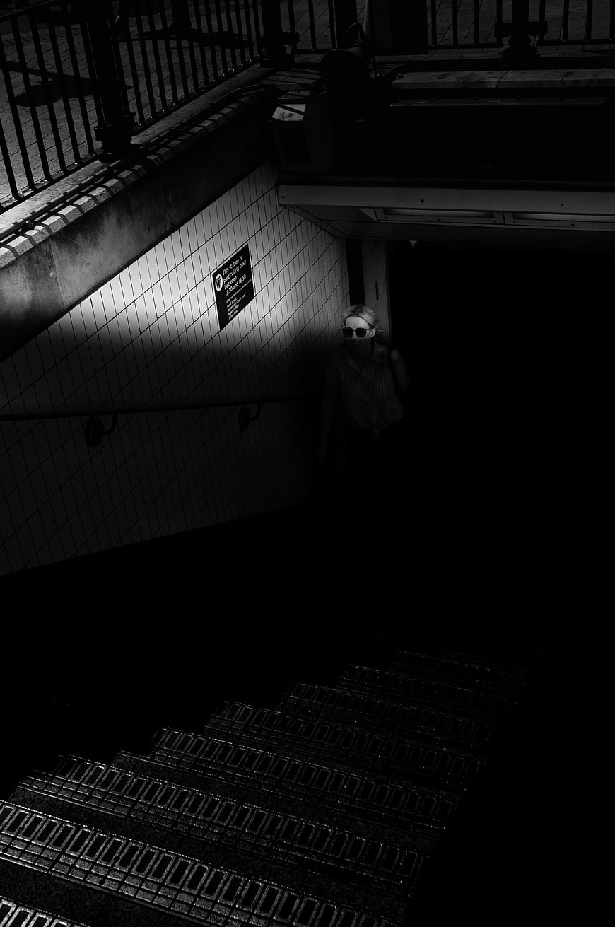Woman in Sunglasses Walking Down Dark Subway Stairs
