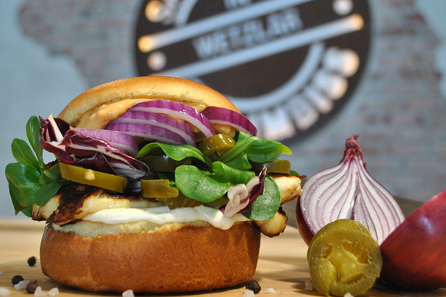 Close-up of vegetarian halloumi burger with red onion and pickles