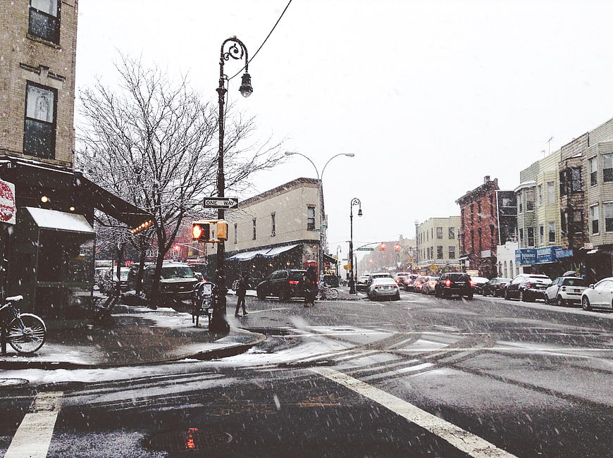 Snowy City Street Intersection with Traffic and Buildings