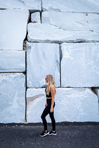 Woman in black activewear walking past large marble blocks