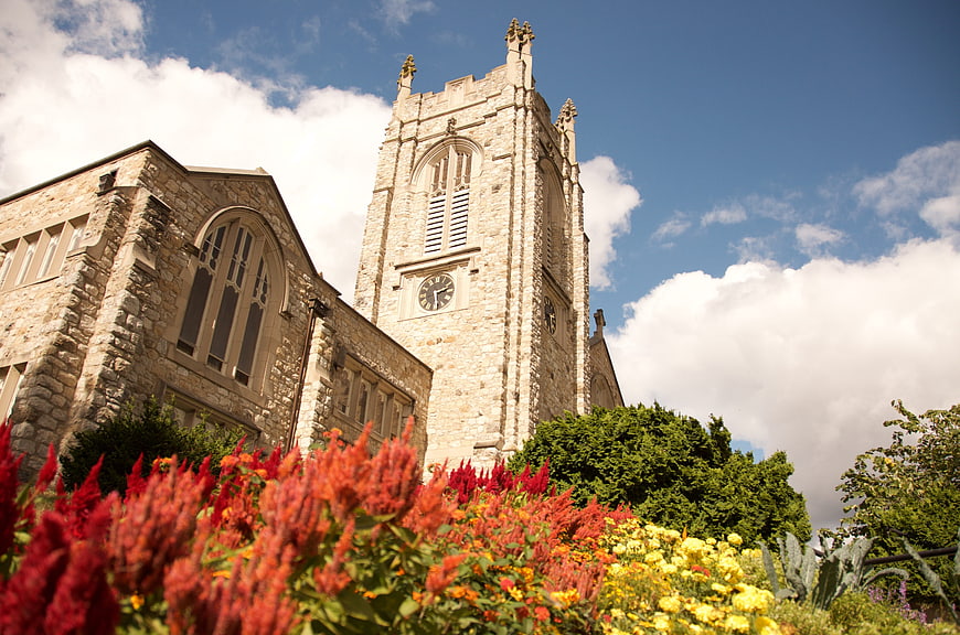 Historic stone church tower with vibrant red and yellow flowers
