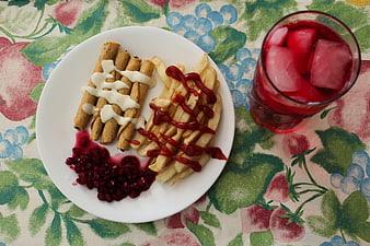 Flat lay of savory rolls, fries, pomegranate, and red juice
