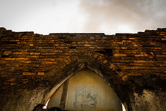 Low angle view of old brick wall with gothic arch