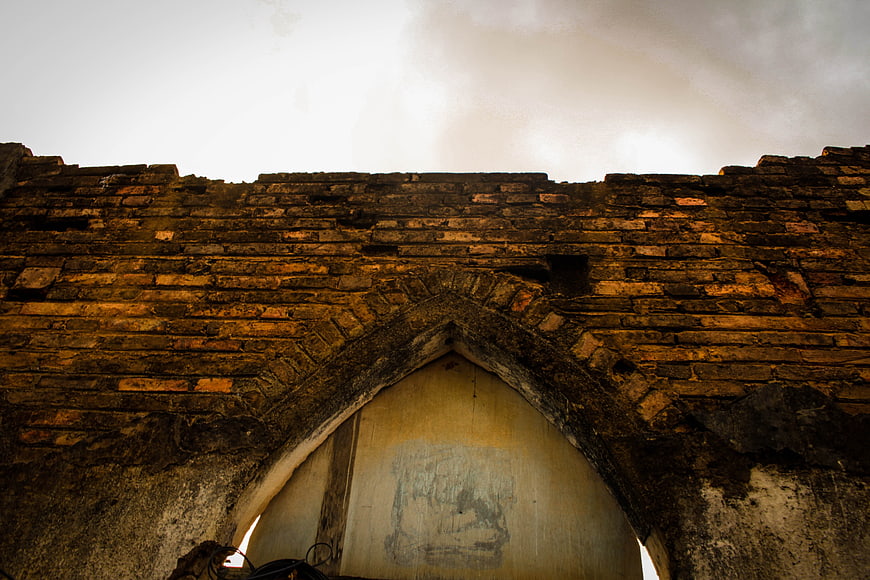 Low angle view of old brick wall with gothic arch