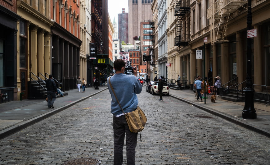 Videographer Filming on Cobblestone City Street