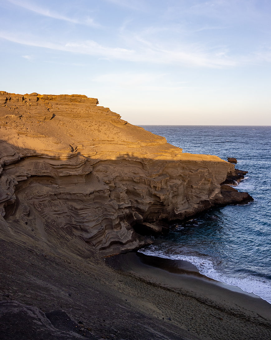 Golden sunlight on layered coastal cliffs and ocean waves