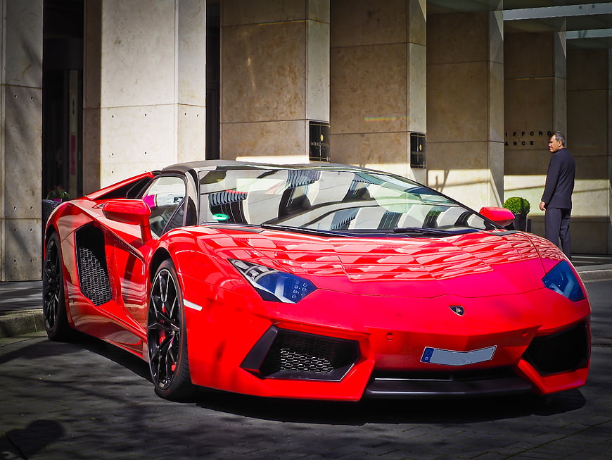 Red Lamborghini Aventador parked in front of luxury hotel
