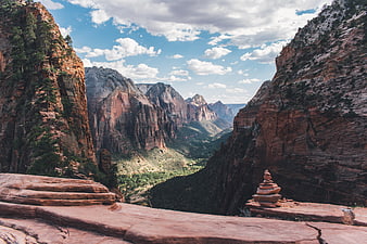 Stacked rocks on red sandstone cliff overlooking canyon