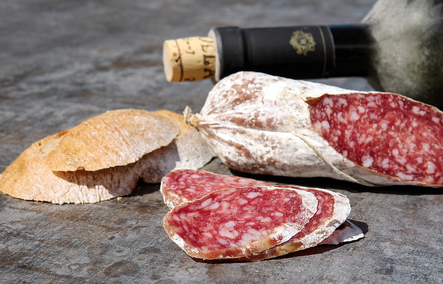 Sliced Salami, Bread, and Wine on Stone Surface