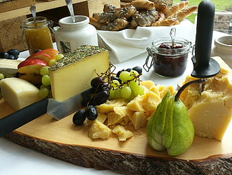 Rustic Cheese Platter With Grapes, Pear, And Pastries On Wooden Board