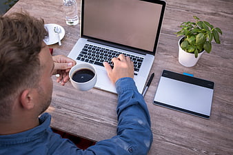 Man working on laptop with coffee and graphics tablet