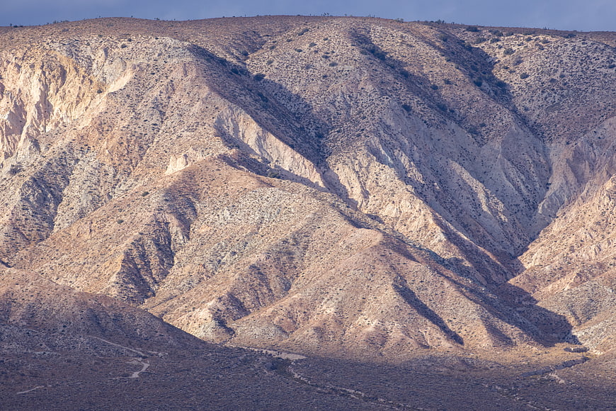 Arid desert mountain landscape with rugged terrain and shadows