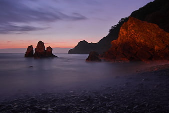 Dramatic Coastal Sunset with Smooth Misty Ocean and Rock Formations