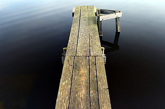 Weathered wooden pier extending into calm dark water