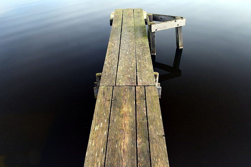 Weathered wooden pier extending into calm dark water