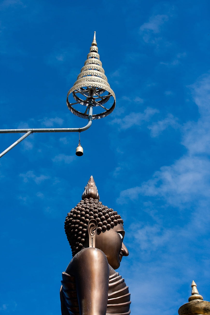 Bronze Buddha Statue and Ornate Umbrella Against Blue Sky