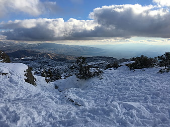 Snowy mountain landscape with dramatic clouds and distant peaks
