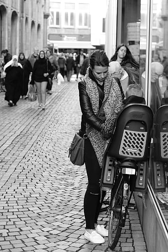 Woman with child seat on bicycle on cobblestone street