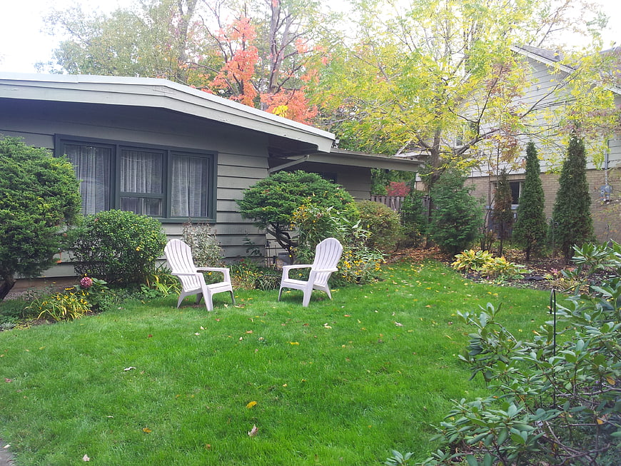 White Adirondack Chairs in Green Backyard Garden