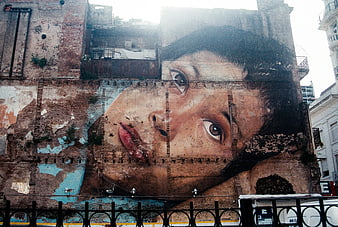 Large mural of a woman's face on a weathered brick wall