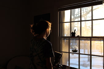 Woman Silhouette Looking Out Window at Snowy Winter Scene