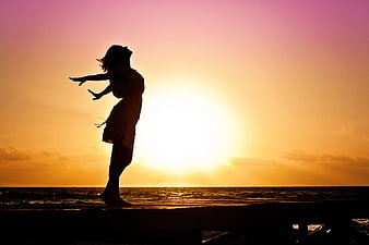 Silhouette of Woman Dancing on Pier at Sunset